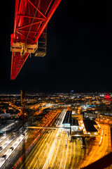 night shot of a crane and urban city with bright lights with long exposure traffic and car lights -...