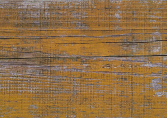 Layers of old chipped yellow, blue and white paint in cracks on a wooden surface. Removing flooring from boards. Repair in the household. Soft focus.