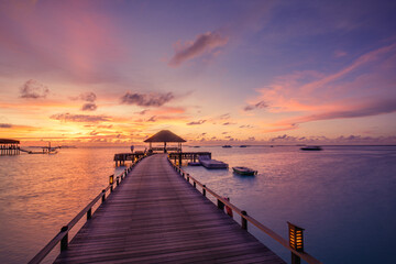 Fototapeta premium Amazing beach landscape. Beautiful Maldives sunset seascape view. Horizon colorful sea sky clouds, over water villa pier pathway. Tranquil island lagoon, tourism travel background. Exotic vacation