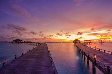 Fototapeta premium Amazing beach landscape. Beautiful Maldives sunset seascape view. Horizon colorful sea sky clouds, over water villa pier pathway. Tranquil island lagoon, tourism travel background. Exotic vacation