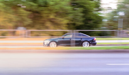 Plakat Dark car driving on the street at sunset. motion blur