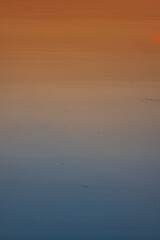 A colorful orange sunset reflects on the water creating a long gradient