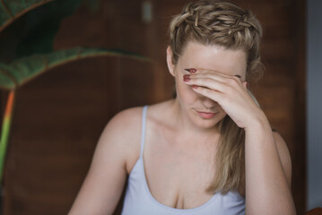 Portrait of a young woman who closes her eyes with her hand. The girl is crying, upset. Negative...