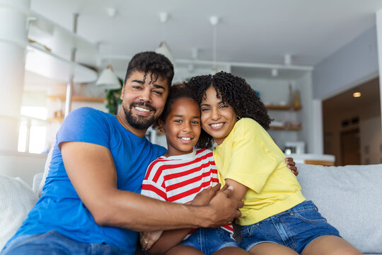 Portrait attractive multi-ethnic wife husband and kid indoors. Close up married couple with little pretty daughter sitting together smiling looking at camera. Concept friendly wellbeing happy family