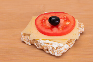 Rice Cake Sandwich with Tomato, Cheese and Olives on Bamboo Cutting Board. Easy Breakfast. Diet Food. Quick and Healthy Sandwiches. Crispbread with Tasty Filling. Healthy Dietary Snack