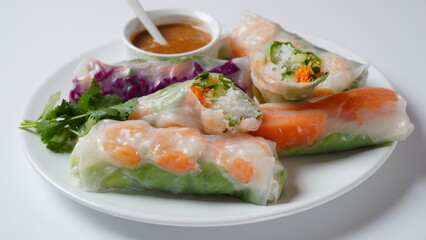 Vietnamese Spring Rolls Goi Cuon or Nem Cuon,  filled with prawns, herbs, rice vermicelli and vegetables. Served with hoisin and peanut sauce dip.