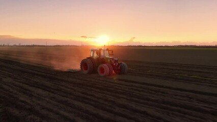 aerial view drone of tractor plowing working the field at dusk sunset,golden light - Powered by Adobe