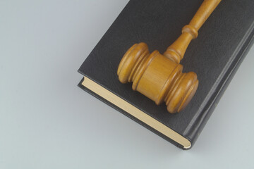 Wooden judge gavel on black legal book on gray background	