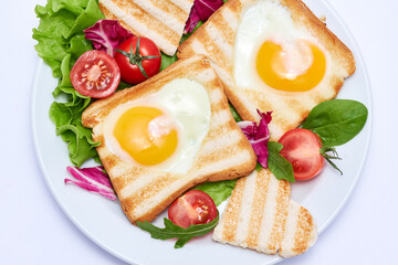 Fried egg Toasts with heart shaped holes on white ceramic plate