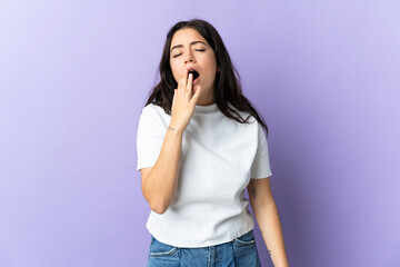 Young caucasian woman isolated on purple background yawning and covering wide open mouth with hand