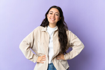 Young caucasian woman isolated on purple background posing with arms at hip and smiling