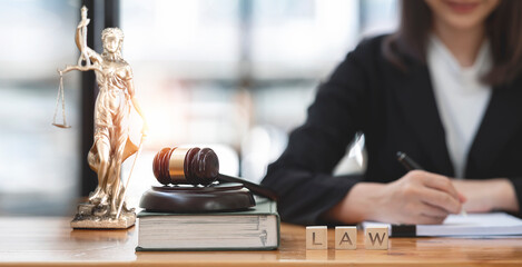 Female lawyers working at the law firms. Judge gavel with on the book and wooden cubes with text LAW. Legal law, lawyer, advice and justice concept.