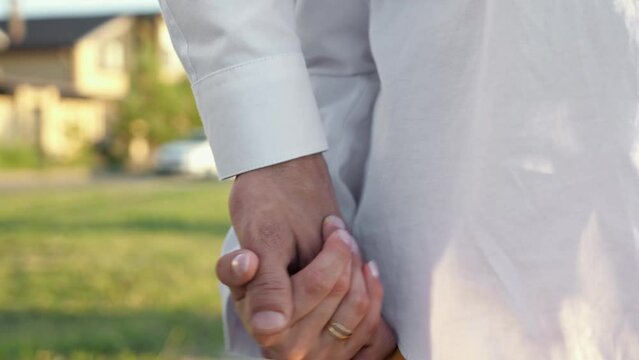Couple with cerebral palsy walks outdoor holding hands against town road. People join hands showing pure love and trust to each other closeup