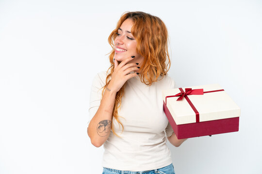 Young caucasian woman holding a gift iso0lated on white background thinking an idea and looking side
