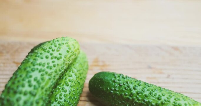Camera flies over green cucumbers lying on a wooden cutting board. Close-up.
