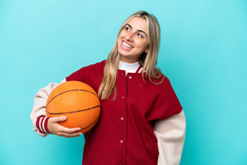 Young caucasian basketball player woman isolated on blue background thinking an idea while looking up