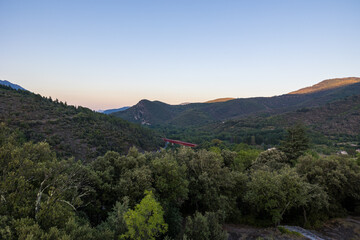 Fototapeta na wymiar Pont ferroviaire d'Olargues devant les montagnes du Parc naturel du Haut-Languedoc au coucher