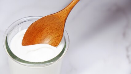 Wooden spoon scooping yogurt from glass