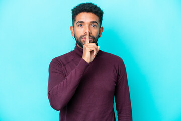 Young Brazilian man isolated on blue background showing a sign of silence gesture putting finger in mouth