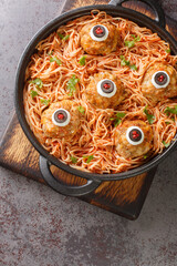 Scary tasty Halloween food of meatballs with monster eyes and spaghetti with tomato sauce in a pan...