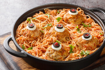 halloween Spaghetti with tomato sauce and meatballs with eyes in a frying pan on the table close-up. Horizontal