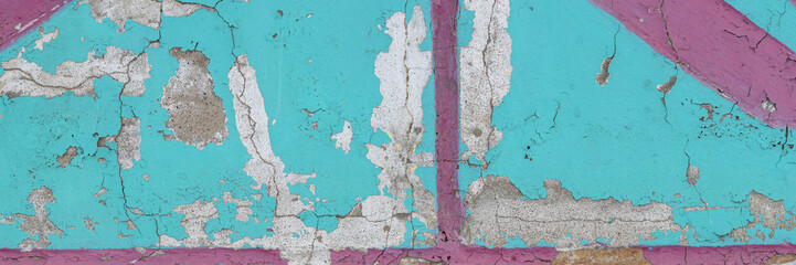 Peeling paint on the wall. Panorama of a concrete wall with old cracked flaking paint. Weathered rough painted surface with patterns of cracks and peeling. Wide panoramic grunge texture for background