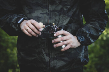 the man is making coffee while camping. manual coffee grinder. in the middle of the forest