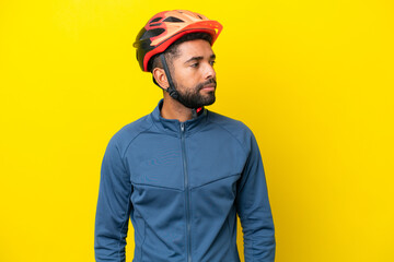 Fototapeta premium Young cyclist Brazilian man isolated on yellow background looking to the side