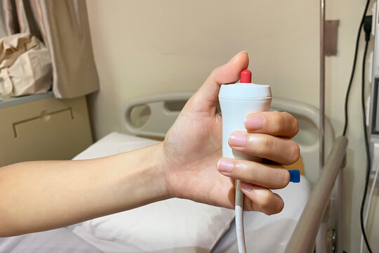 Lady patient using nurse call button for emergenvy bell in hospita wardl. Nusre call button. Hand in saline solution injection.