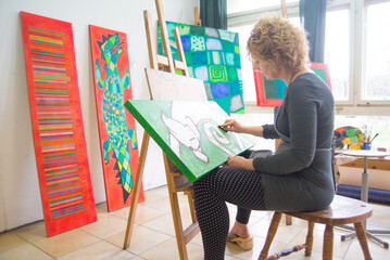 Female artist painting abstract painting in her professional studio