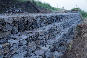 gabions for Landslide resisting system, a rock structure that is held in place by woven steel wire coated with zinc or galvanized.