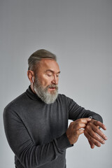 Senior concentrated man watch time on smartwatch