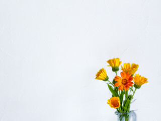 A bouquet of yellow and orange calendula flowers on a white background. Space for copying. A business card. An invitation card. A place for a congratulatory text. Mockup. Banner. Hello, August