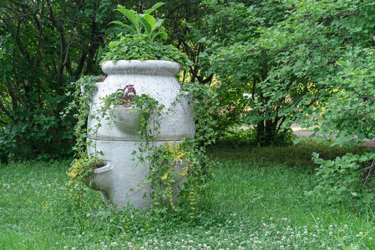 Antique stone vase with garden flowers in a summer park. © Valemaxxx