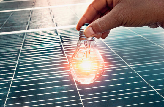 hand holding lightbulb on solar panel concept clean energy in nature.