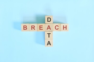 Data breach concept. Wooden block crossword puzzle flat lay in blue background.