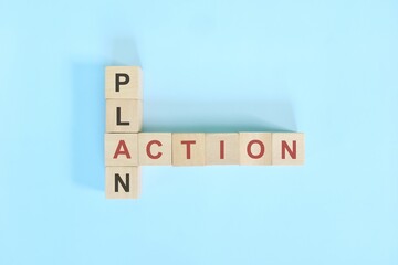 Action plan business concept. Wooden block crossword puzzle flat lay in blue background.