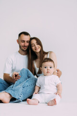 Happy young family. Beautiful Mother and father kissing their baby . Parents, Portrait of Mom, dad and smiling child on hands isolated over white background.