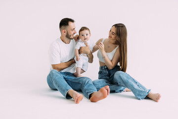 Obraz na płótnie Canvas Family portrait of happy smiling mother, father playing on the floor with baby over white background