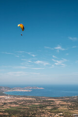 A tandem paraglider flies over the bay of Calvi in the Balagne region of Corsica