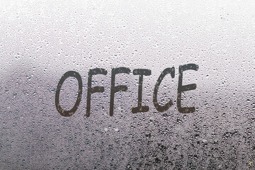 the word office written on night wet window glass close-up with blurred background