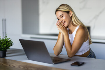 Fototapeta premium Cute smiling woman using laptop at home. Student girl working on computer. Online shopping, work from home, freelance, online learning, studying, lockdown concept. Distance education