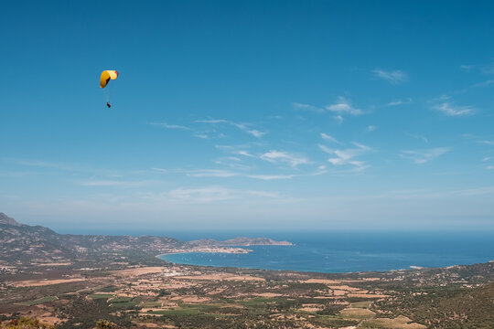 A tandem paraglider flies over the bay of Calvi in the Balagne region of Corsica