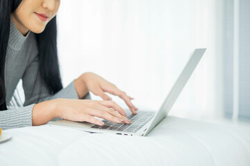 Beautiful asian eat show pizza and cola drink on bed. Happy woman sitting eating fast food. Lovely young working on laptop from home hand holding with junk food and soft drink showing. out of focus.