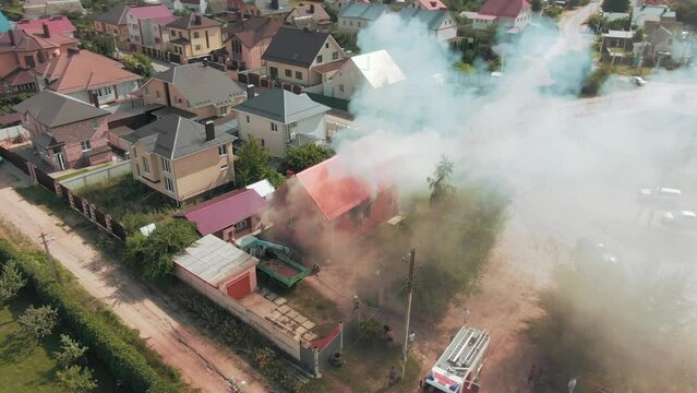 Aerial video footage of a fire. Red house. Smoke from the windows. Residential area. Emergency call. 4k drone footage.