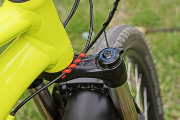 part of a yellow sports bike from a metal fork spring on a black wheel on the street on a green...