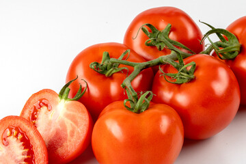Fototapeta premium Six red fresh tomatoes on a branch and two half tomatoes isolated on white background. Fresh tomatoes on white background.