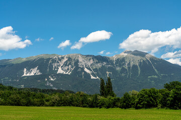 Beautiful panorama view of Veliki Stol (Hochstuhl) massif at border between Slovenia and Austria on a sunny summer day from Bled with blue sky cloud. - 520177487
