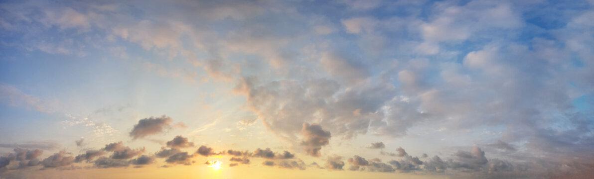Warm yellow sunrise sky with dramatic clouds, panoramic background