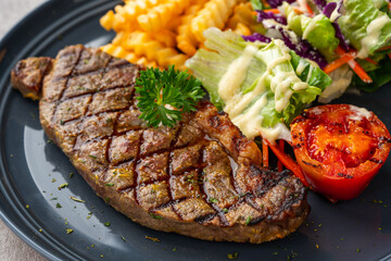 Grilled Sirloin Beef Steak with french fries and salads. Serve on Black Plate. Negative Space.